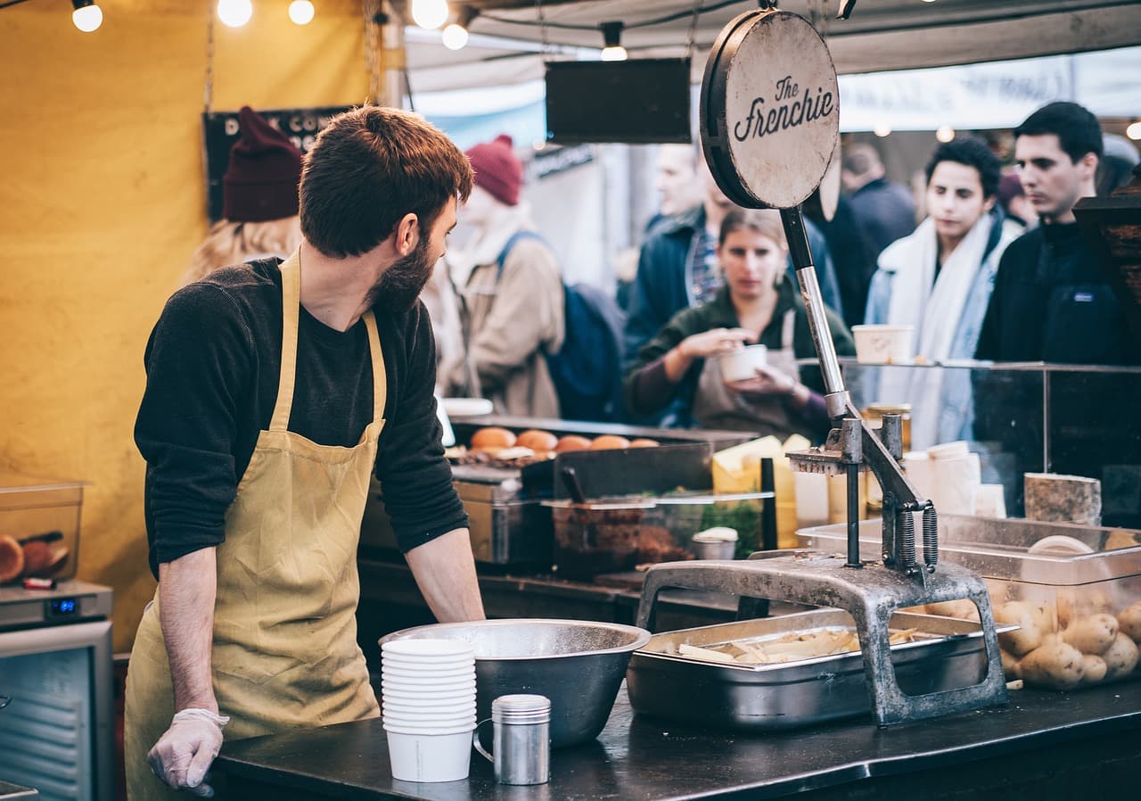 Stand de street food sur un marché, avec des clients qui attendent leur commande